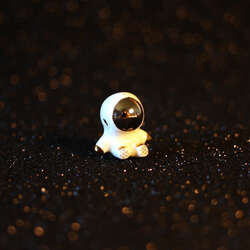 Hand sculpted sitting astronaut figurine with 22k gold and palladium details. 